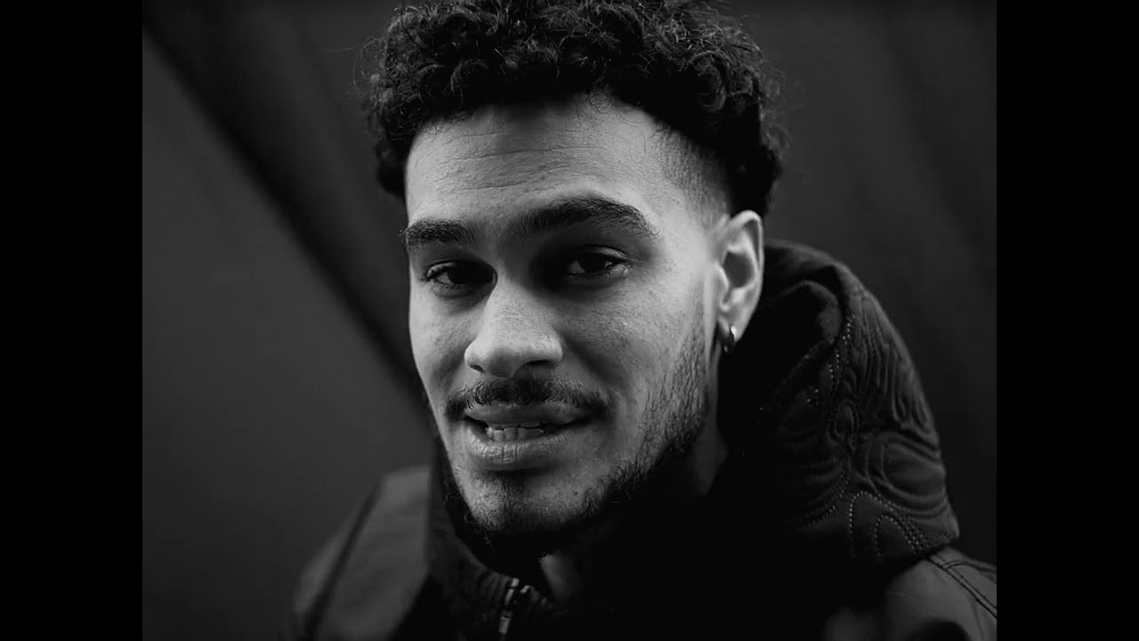 Still from the Faith video: a black and white close-up of OSK, half smiling, in a dark hoodie.